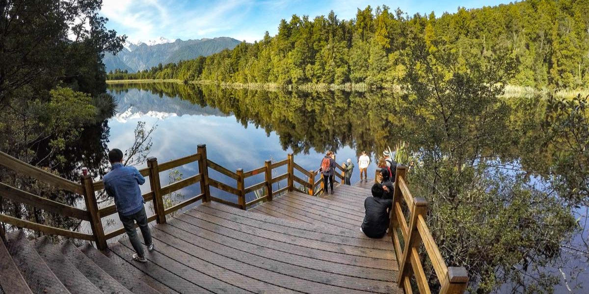 Steps into Lake Matheson with stunning reflection views