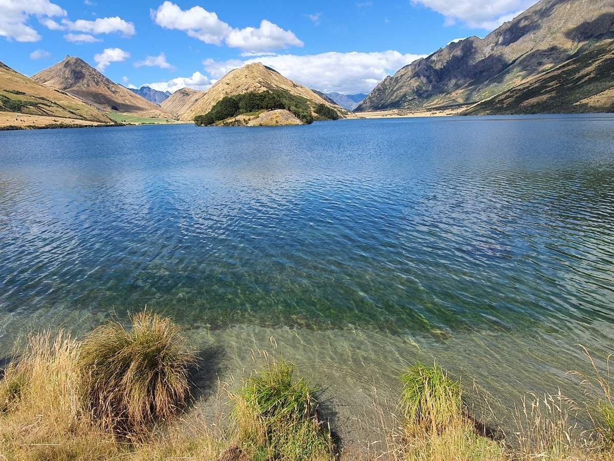 Crystal clear turquoise water at Moke Lake with the peninsula and mountains behind, Queenstown