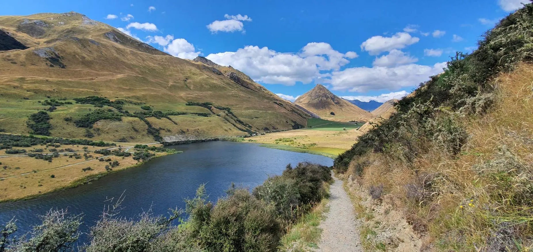Walking track on the Moke Lake loop with the lake below and pyramid-shaped mountain peak behind, Queenstown