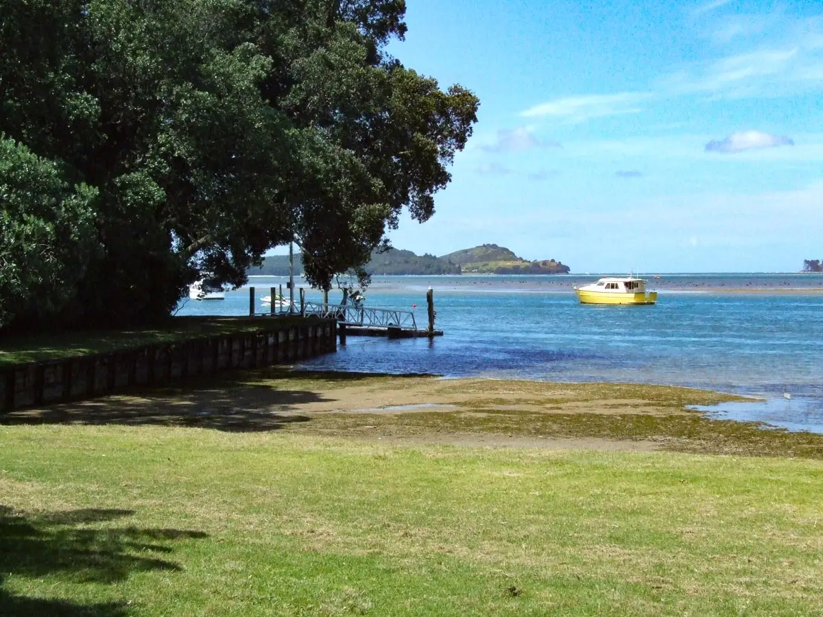Tanners Point jetty and tidal beach on Tauranga Harbour near Katikati with boats moored in the channel