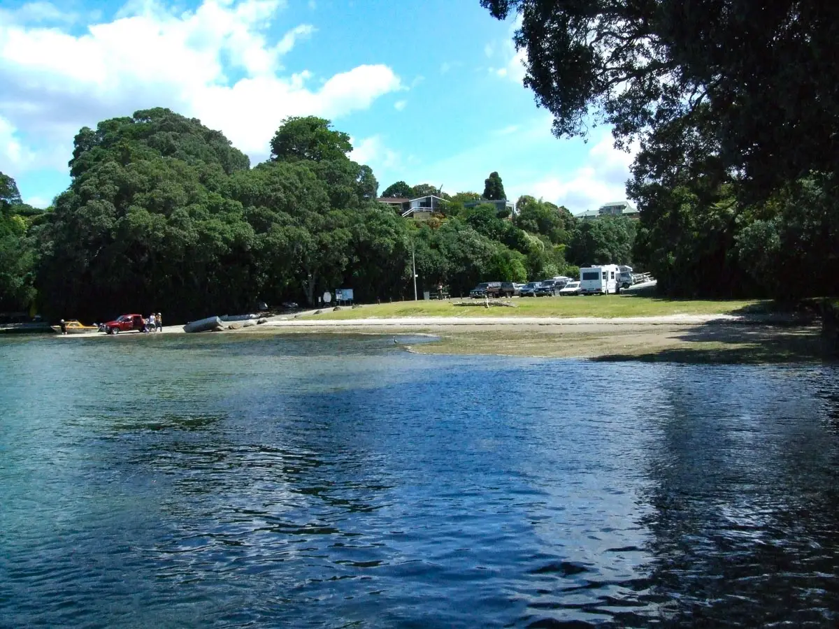 anners Point Reserve from the water showing the boat ramp, overnight parking area with campervans, and pohutukawa trees