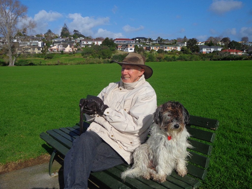 A man with his dog sitting on the bench chilling at the Churchill Park