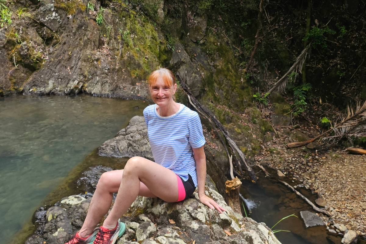 sandra sit on the rock beside waterfall