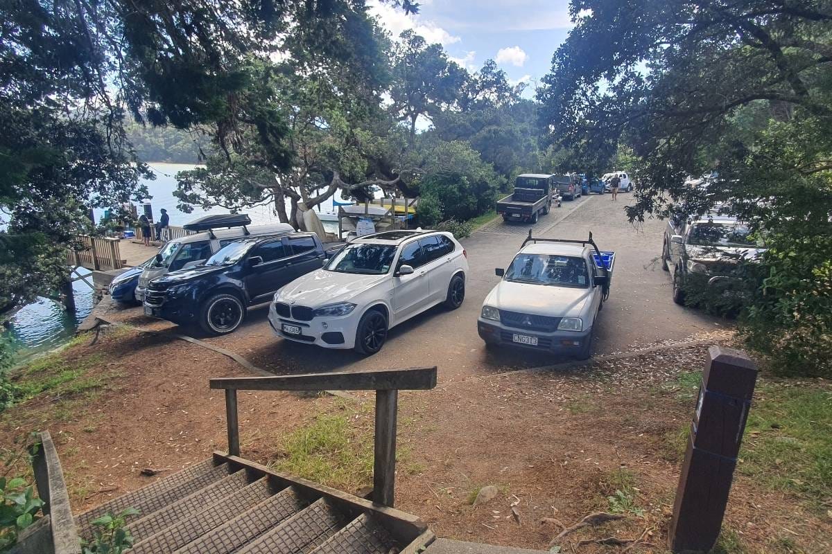 a line of cars parked next to a lake on a sunny day