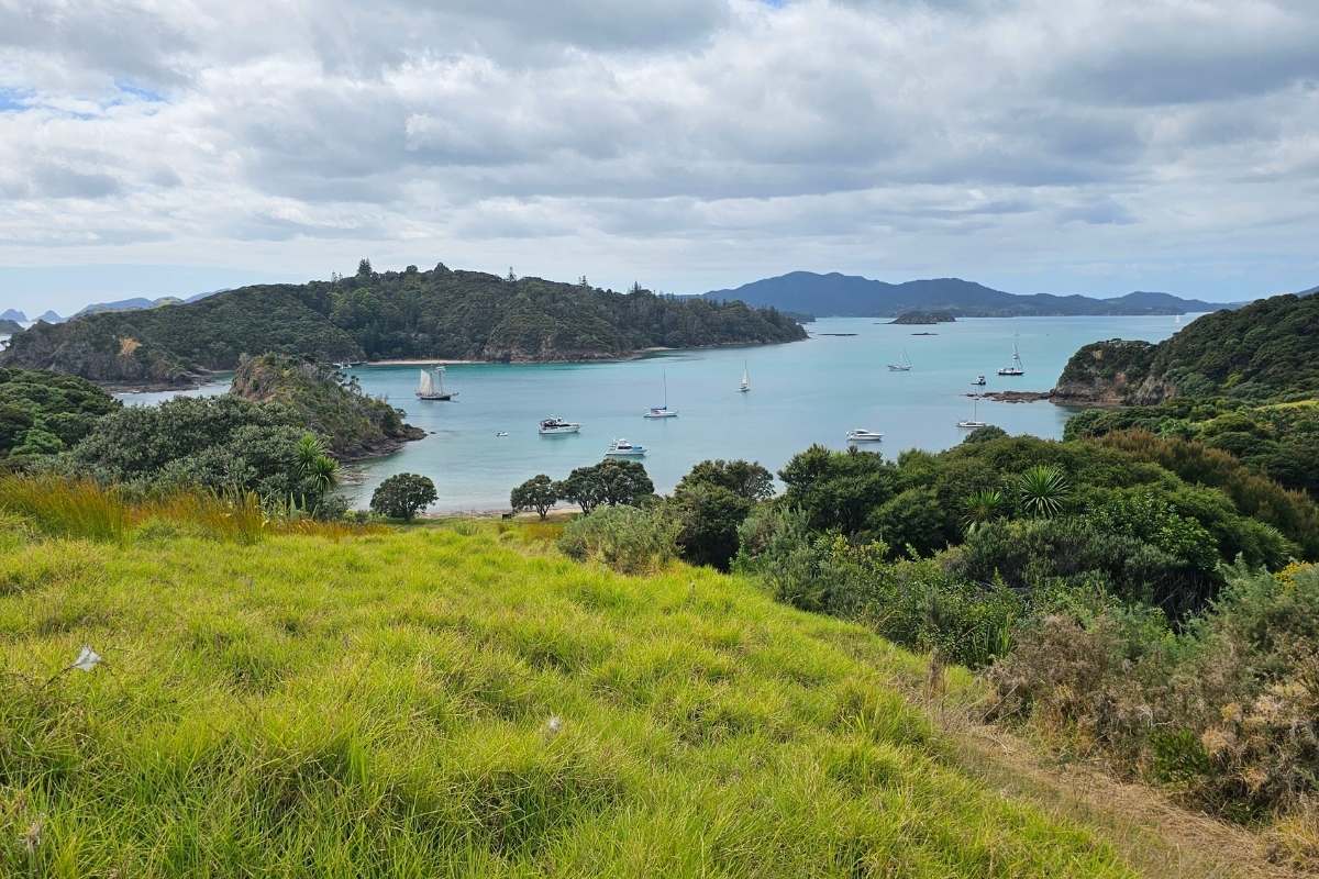 Panoramic view across turquoise bay with anchored boats and distant
mountains