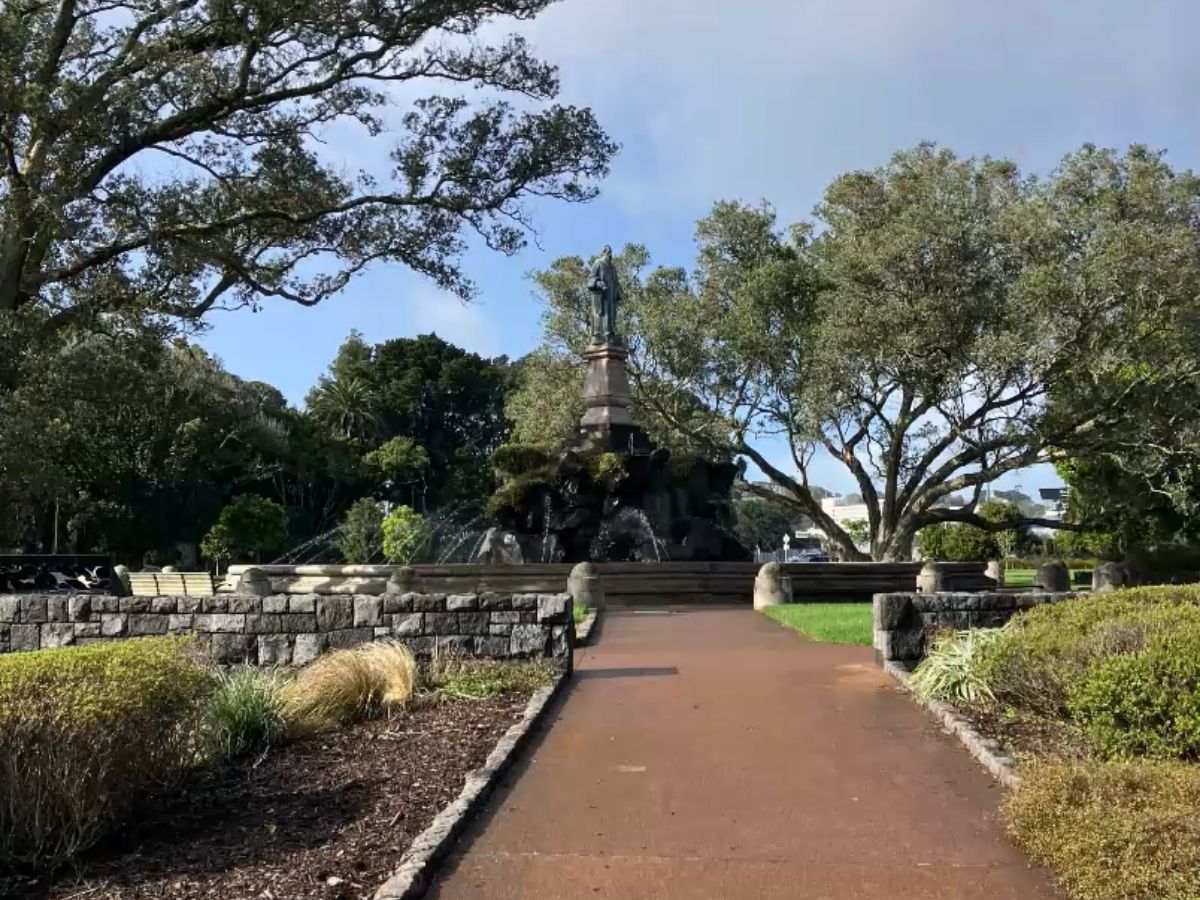 Sir John Logan Campbell statue on fountain with water features, framed by mature trees at Cornwall Park entrance on Manukau Road